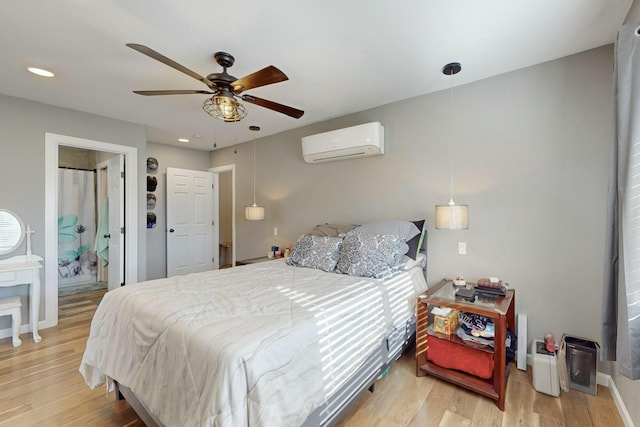 bedroom featuring ceiling fan, wood-type flooring, connected bathroom, and a wall mounted AC