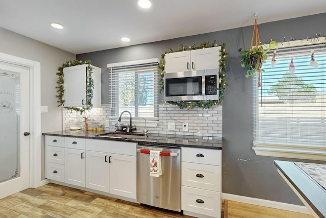 kitchen featuring white cabinetry, sink, stainless steel appliances, light hardwood / wood-style flooring, and decorative backsplash