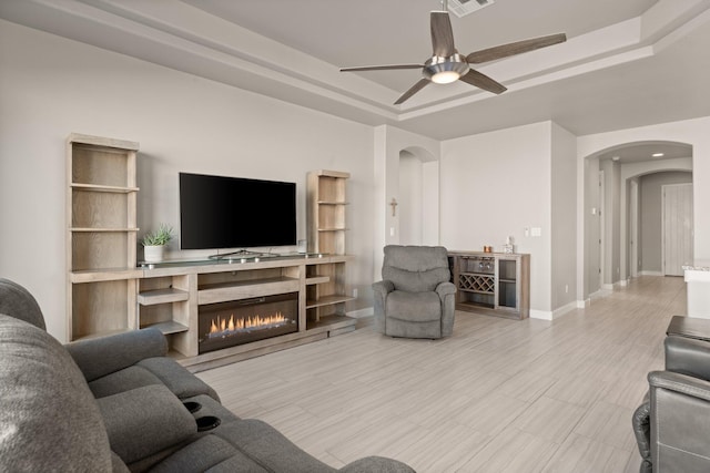 living room with ceiling fan and a tray ceiling