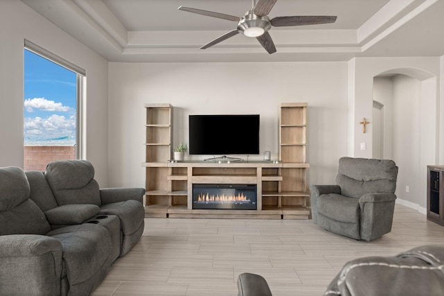 living room with a raised ceiling and ceiling fan