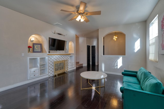 living room featuring a fireplace, ceiling fan, built in features, and dark wood-type flooring