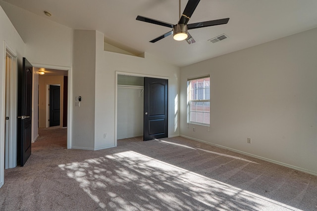 unfurnished bedroom featuring ceiling fan, a closet, light colored carpet, and lofted ceiling