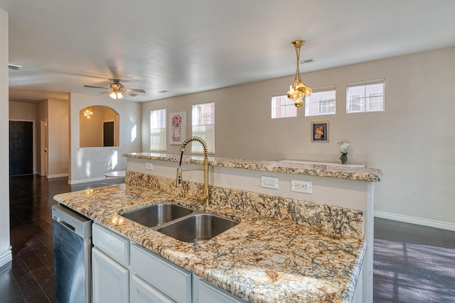 kitchen featuring dishwasher, a center island with sink, sink, ceiling fan, and light stone countertops