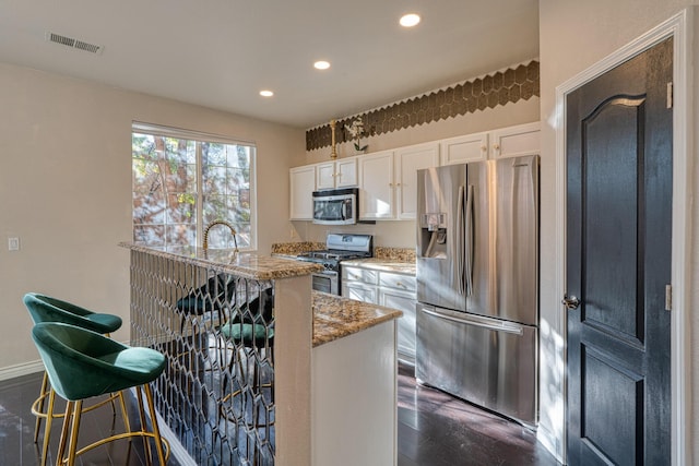 kitchen featuring light stone countertops, a kitchen breakfast bar, stainless steel appliances, dark wood-type flooring, and white cabinets