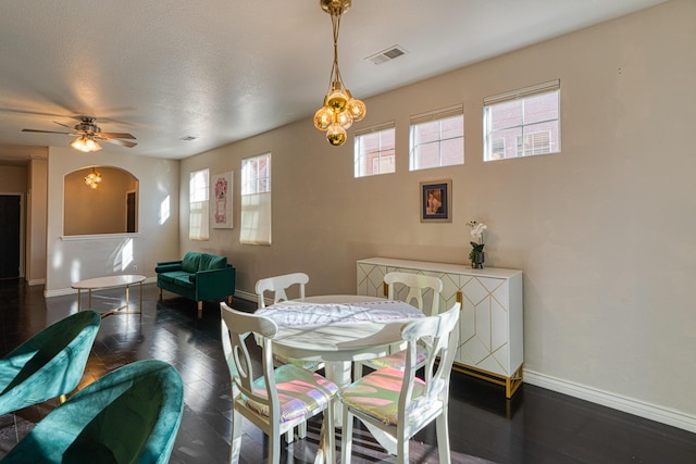 dining space with a textured ceiling, ceiling fan with notable chandelier, and dark hardwood / wood-style floors