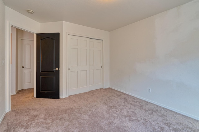 unfurnished bedroom featuring a closet and light colored carpet