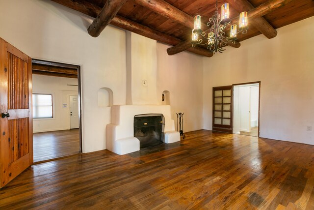 unfurnished living room featuring wooden ceiling, dark hardwood / wood-style flooring, beam ceiling, and a notable chandelier