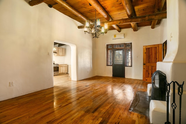 unfurnished living room with light wood-style flooring, beamed ceiling, wood ceiling, and an inviting chandelier