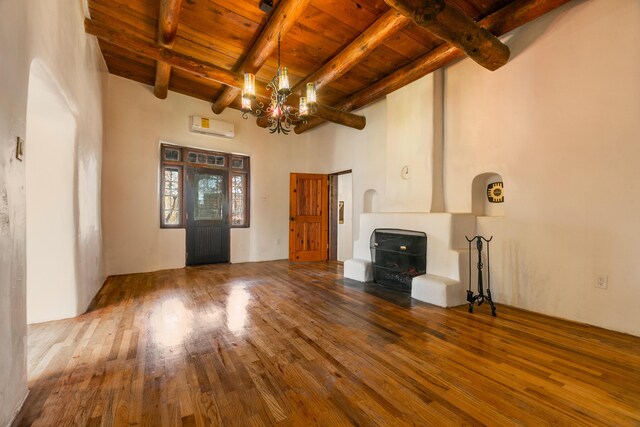 unfurnished living room featuring a wall mounted AC, a notable chandelier, hardwood / wood-style flooring, wooden ceiling, and beam ceiling