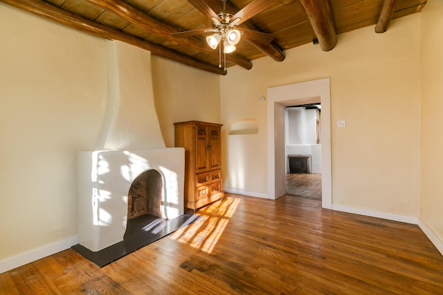 unfurnished living room with beam ceiling, wood finished floors, wood ceiling, and baseboards