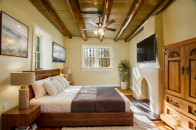 bedroom featuring beamed ceiling, wood finished floors, and wood ceiling