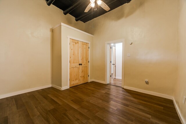 bedroom featuring dark wood-type flooring, ceiling fan, beam ceiling, and a high ceiling