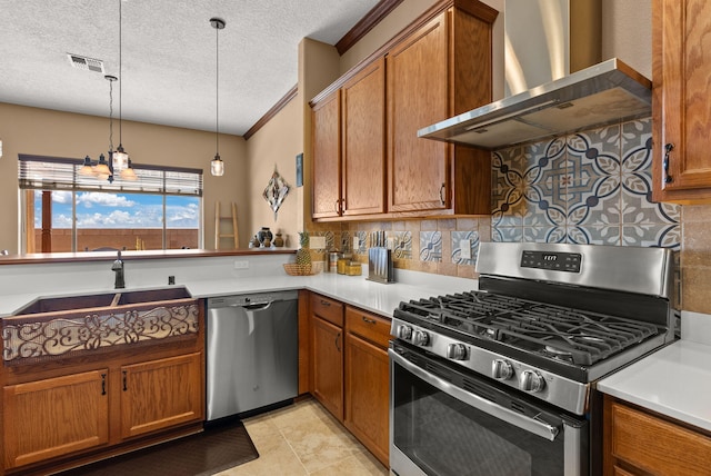 kitchen with sink, wall chimney exhaust hood, decorative backsplash, appliances with stainless steel finishes, and decorative light fixtures