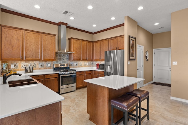 kitchen featuring a kitchen bar, tasteful backsplash, wall chimney exhaust hood, stainless steel appliances, and sink