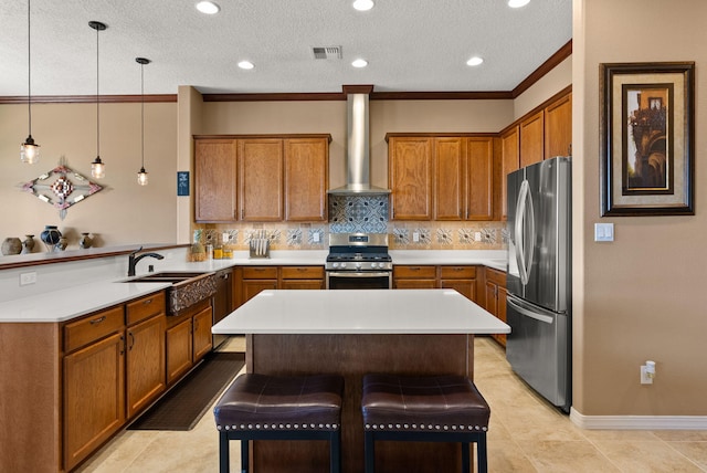 kitchen with appliances with stainless steel finishes, backsplash, wall chimney exhaust hood, hanging light fixtures, and a breakfast bar area