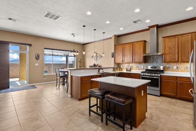 kitchen featuring a kitchen bar, stainless steel gas stove, a kitchen island, and wall chimney exhaust hood