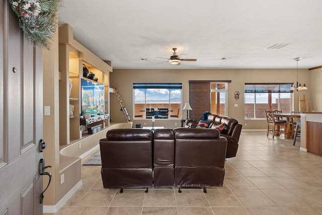 living room with light tile patterned floors, ceiling fan with notable chandelier, and a textured ceiling