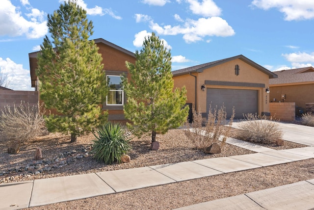 view of front of home with driveway, a garage, fence, and stucco siding