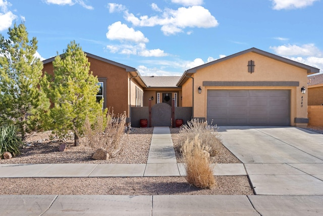 view of front of home featuring concrete driveway, an attached garage, a gate, and stucco siding