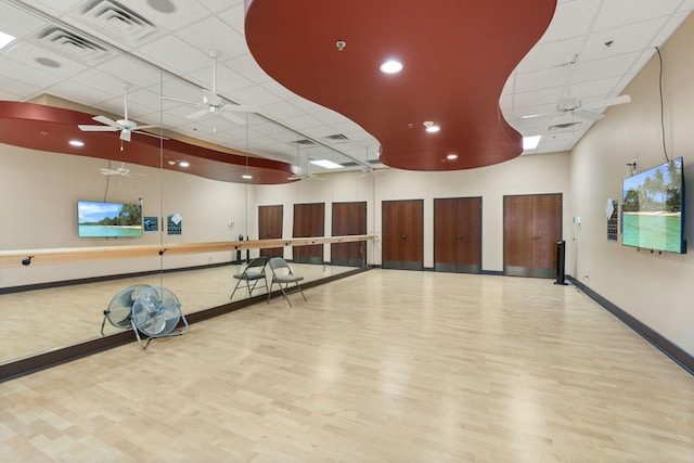 exercise room with a ceiling fan, visible vents, baseboards, and wood finished floors