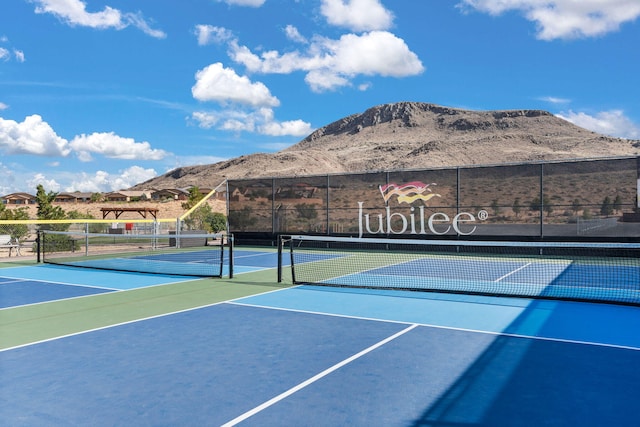 view of tennis court featuring basketball hoop and a mountain view