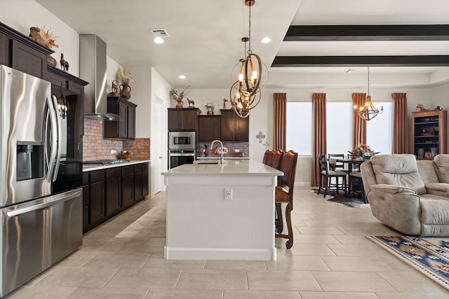 kitchen with light countertops, an inviting chandelier, appliances with stainless steel finishes, open floor plan, and extractor fan