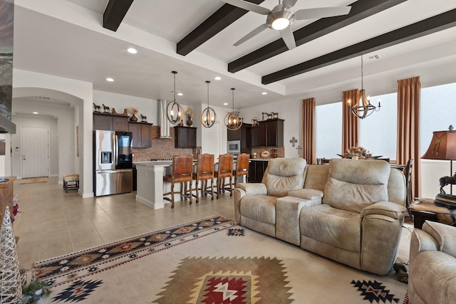 living area with light tile patterned floors, arched walkways, recessed lighting, ceiling fan with notable chandelier, and beamed ceiling