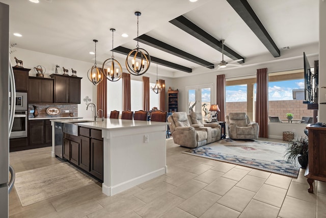 kitchen featuring open floor plan, stainless steel appliances, backsplash, and dark brown cabinetry