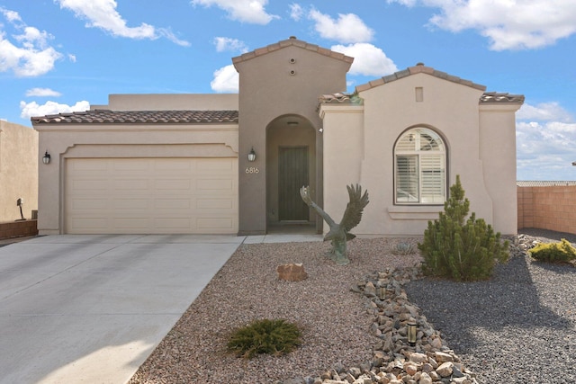 mediterranean / spanish home featuring stucco siding, fence, a garage, driveway, and a tiled roof