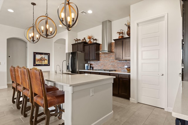 kitchen featuring arched walkways, stainless steel appliances, ventilation hood, and a sink