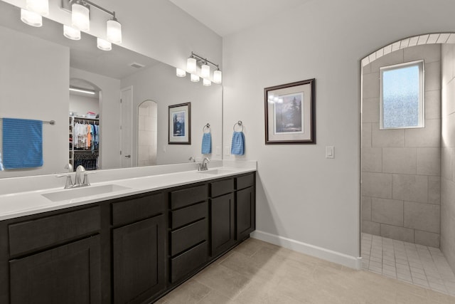 full bathroom with a walk in closet, double vanity, a walk in shower, and a sink