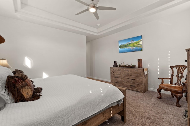 bedroom with a raised ceiling, carpet, baseboards, and ceiling fan