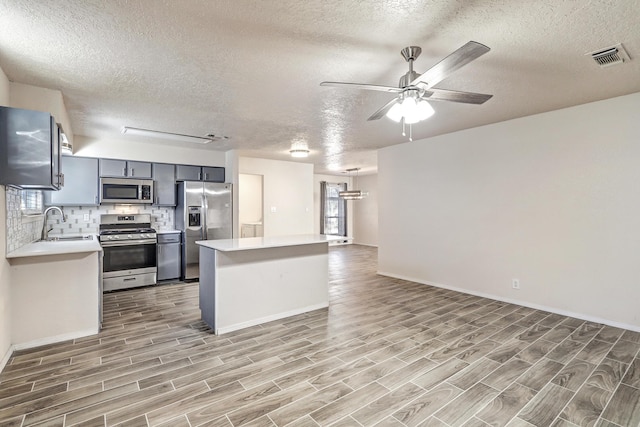 kitchen with a peninsula, appliances with stainless steel finishes, light countertops, and a sink