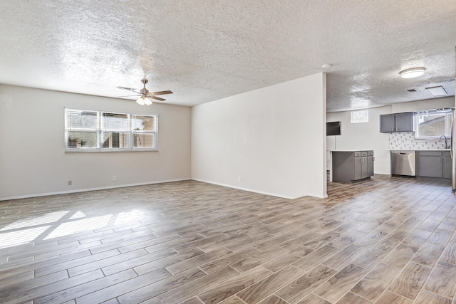 unfurnished living room featuring ceiling fan, sink, wood-type flooring, and a textured ceiling