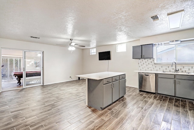 kitchen with light wood-style flooring, a kitchen island, visible vents, light countertops, and dishwasher