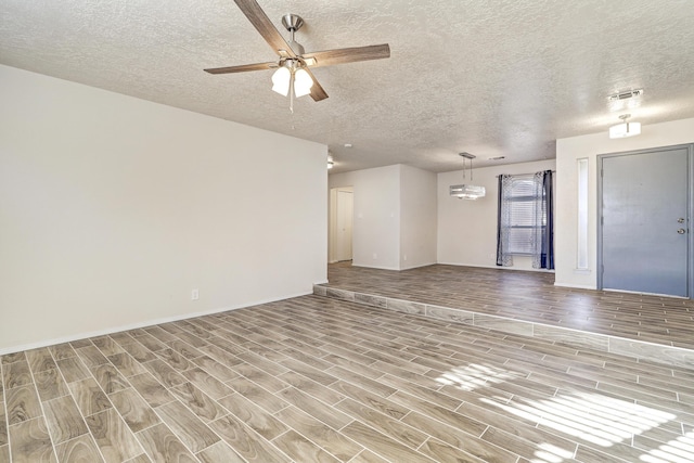 unfurnished living room with ceiling fan, visible vents, a textured ceiling, and wood finish floors