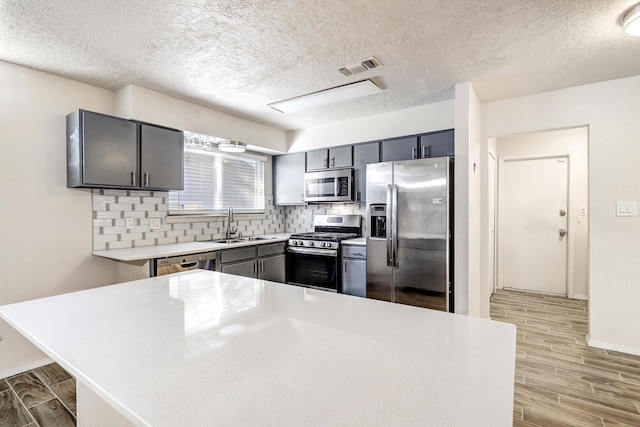 kitchen featuring stainless steel appliances, visible vents, light countertops, wood tiled floor, and tasteful backsplash