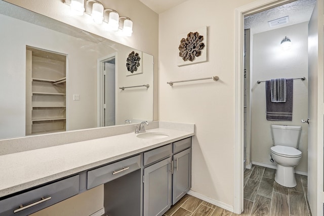 full bathroom with wood finish floors, visible vents, toilet, vanity, and baseboards