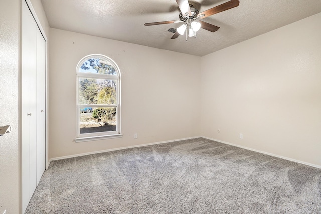 spare room featuring carpet floors, ceiling fan, baseboards, and a textured ceiling