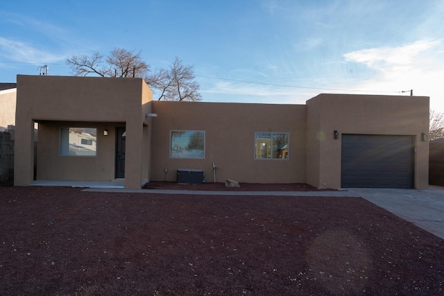 pueblo-style house featuring central AC unit and a garage