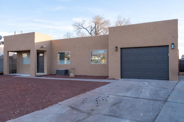 pueblo revival-style home with central AC unit and a garage