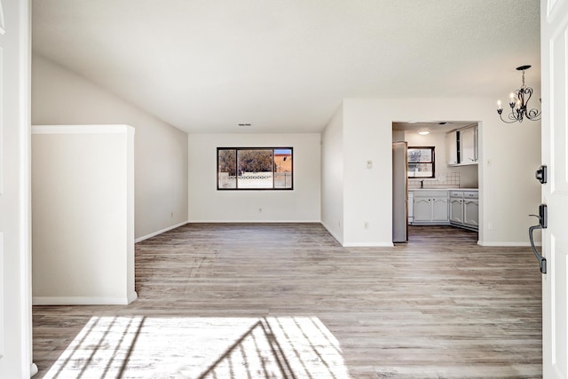 unfurnished living room featuring hardwood / wood-style floors, a chandelier, and sink