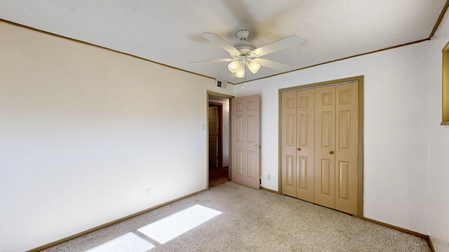 unfurnished bedroom with light carpet, crown molding, a closet, and ceiling fan