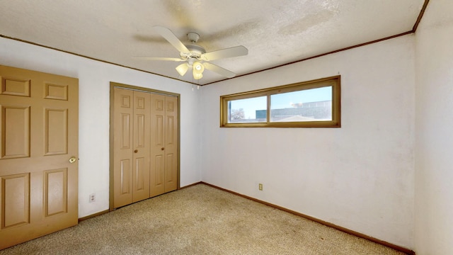 unfurnished bedroom featuring ornamental molding, ceiling fan, light carpet, a textured ceiling, and a closet