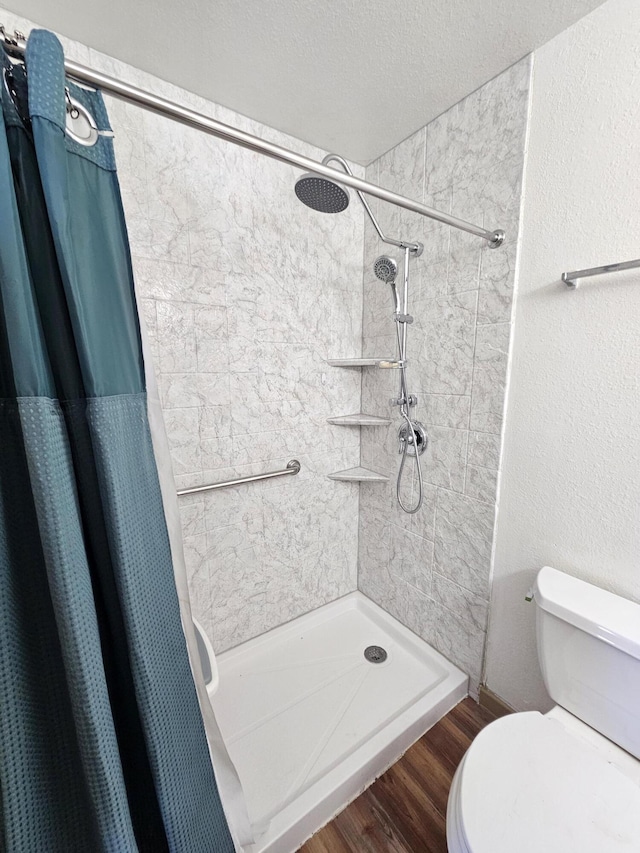 bathroom with hardwood / wood-style floors, curtained shower, a textured ceiling, and toilet