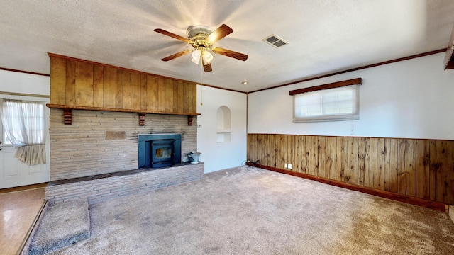 unfurnished living room with a wealth of natural light, carpet, a textured ceiling, and wood walls