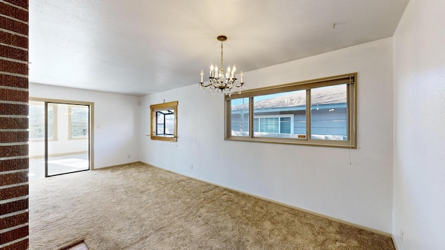 carpeted spare room with a chandelier