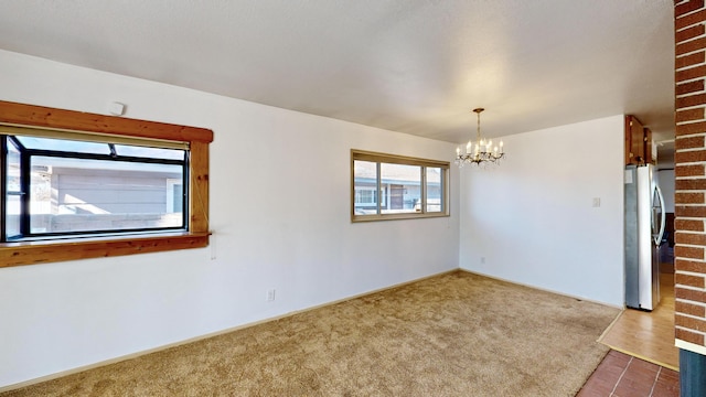 carpeted empty room featuring a notable chandelier