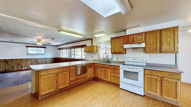 kitchen with white electric range oven, sink, a skylight, wooden walls, and kitchen peninsula