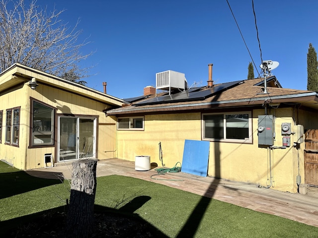 rear view of property with cooling unit, a yard, a patio area, and solar panels